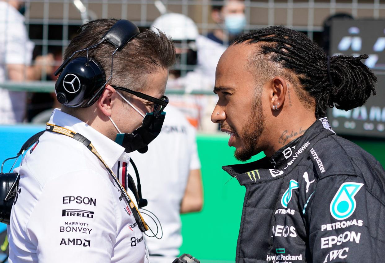 Lewis Hamilton speaks with a member of his team.