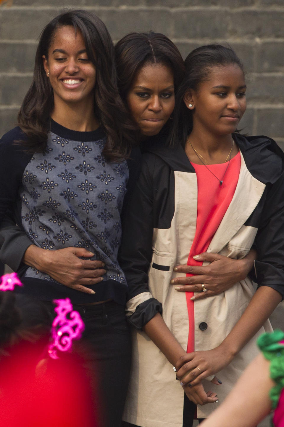 First lady Michelle Obama hugs her daughters Malia and Sasha when they watch a performance during their visit to an ancient city wall in Xi'an, in northwestern China's Shaanxi province, Monday, March 24, 2014.