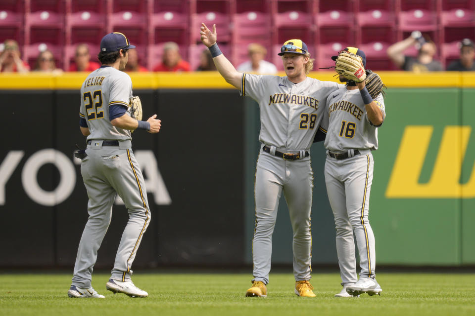 Milwaukee Brewers' Christian Yelich (22) celebrates with Joey Wiemer (28) and Blake Perkins (16) following a baseball game against the Cincinnati Reds in Cincinnati, Sunday, June 4, 2023. (AP Photo/Jeff Dean)