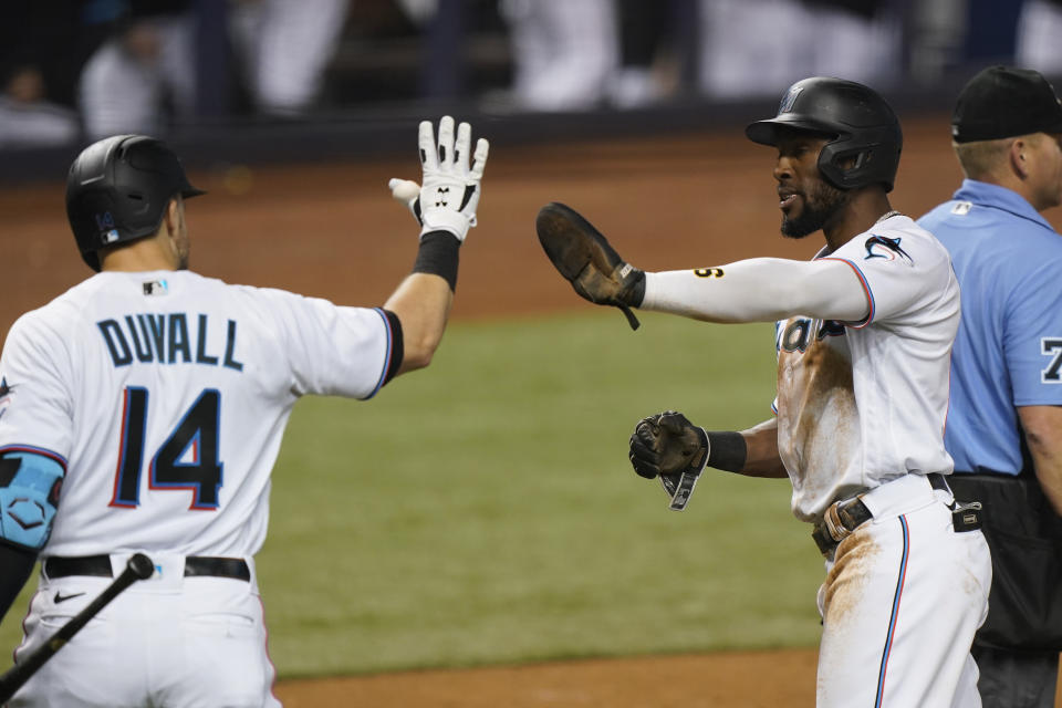 Miami Marlins' Starling Marte, second from right, is congratulated by Adam Duvall (14) after scoring on a single by Garrett Cooper during the third inning of a baseball game against the Los Angeles Dodgers, Monday, July 5, 2021, in Miami. (AP Photo/Wilfredo Lee)