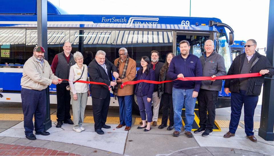Ken Savage, Fort Smith Transit director, center, cuts the ribbon for a new bus with Mayor George McGill and other city officials Monday, Nov. 28, 2022 that was ready for service.