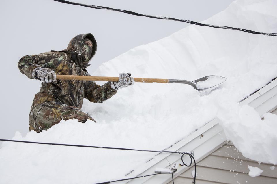 TJ Zydel works to clear his roof in the town of West Seneca near Buffalo, New York