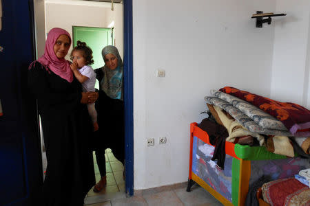 A Syrian woman carrying her daughter looks on, as she stays in a former Peloponnese tourist resort that has been turned into a migrant home near the town of Myrsini, southwest of Athens, Greece, August 13, 2016. Picture taken August 13, 2016. REUTERS/Michele Kambas