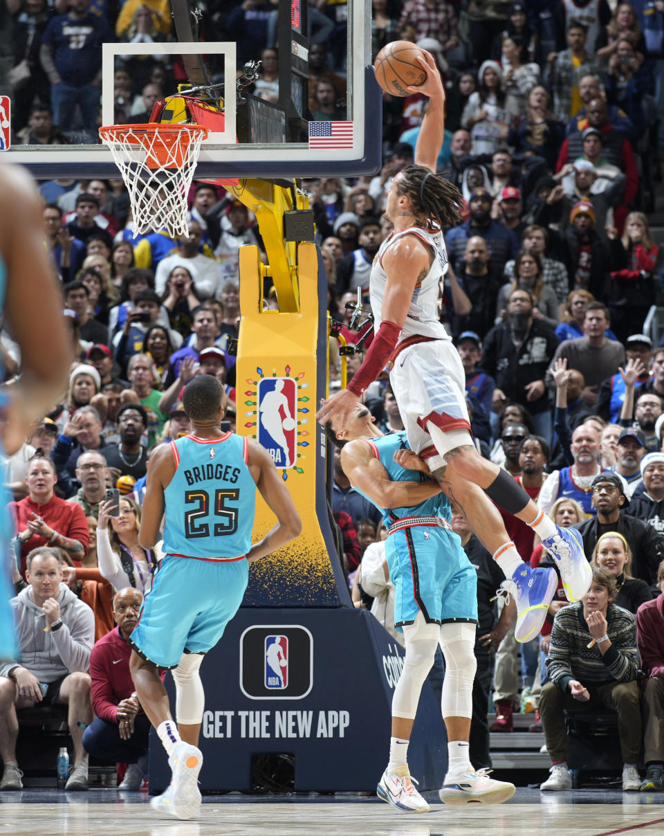 Denver Nuggets forward Aaron Gordon, right, flies over Phoenix Suns guard Landry Shamet to dunk the ball for a basket in overtime of an NBA basketball game Sunday, Dec. 25, 2022, in Denver. (AP Photo/David Zalubowski)