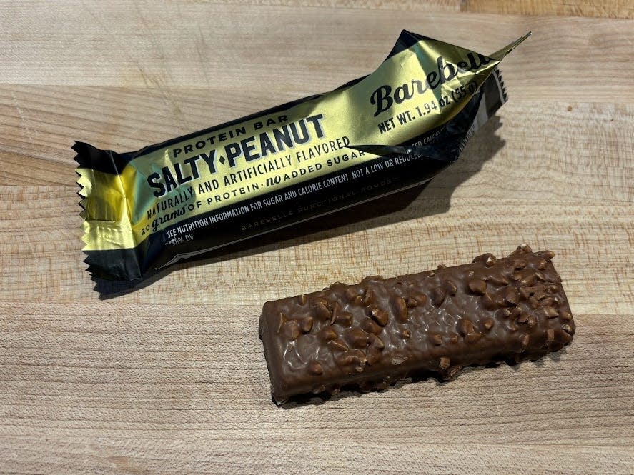 Gold protein bar wrapper with unwrapped bar next to it 
