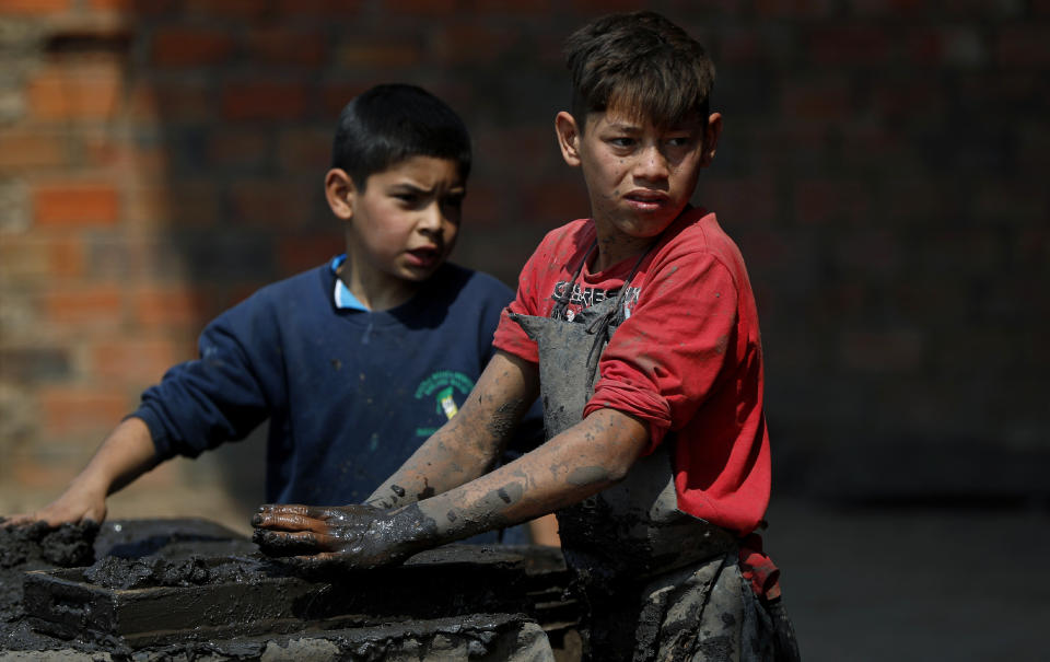 Mauri, 11, left, and Cesar, 13, work at a clay brick factory in Tobati, Paraguay, Friday, Sept. 4, 2020. The boys have been working at the factory, run by Mauri's family, since before schools stopped operating in March amid the COVID-19 pandemic. (AP Photo/Jorge Saenz)