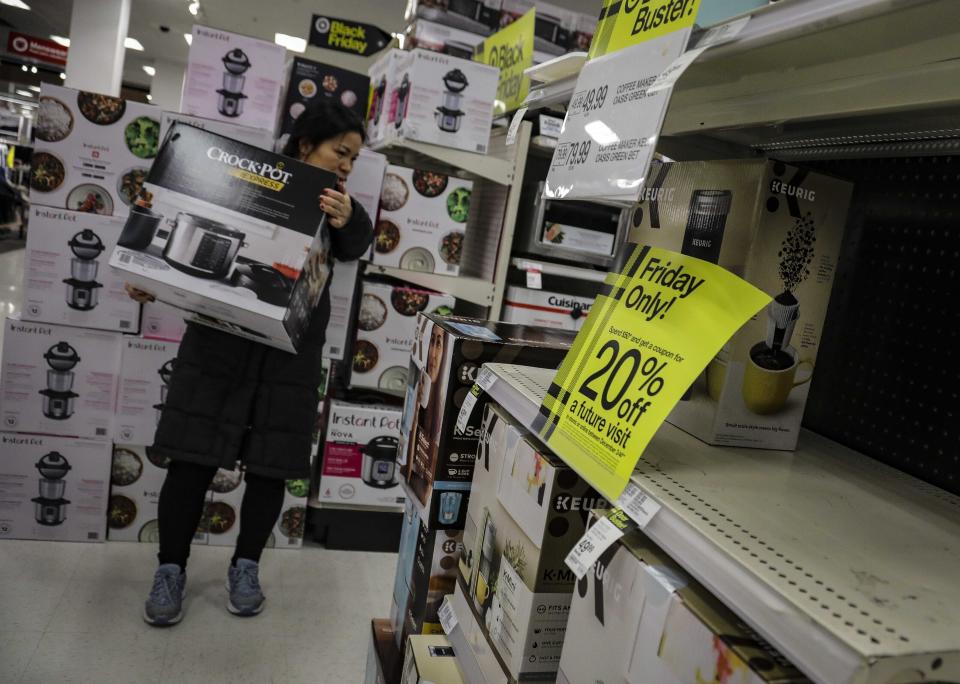 FILE - In this Nov. 29, 2019, file photo a shopper carries a crockpot during Target's Black Friday sale in the Borough of New York. Shopping at sales and using coupons may not be saving you as much money as you think. Knowing the pitfalls and having a plan can help keep your holiday shopping from coming back to bite you in January. (AP Photo/Bebeto Matthews, File)