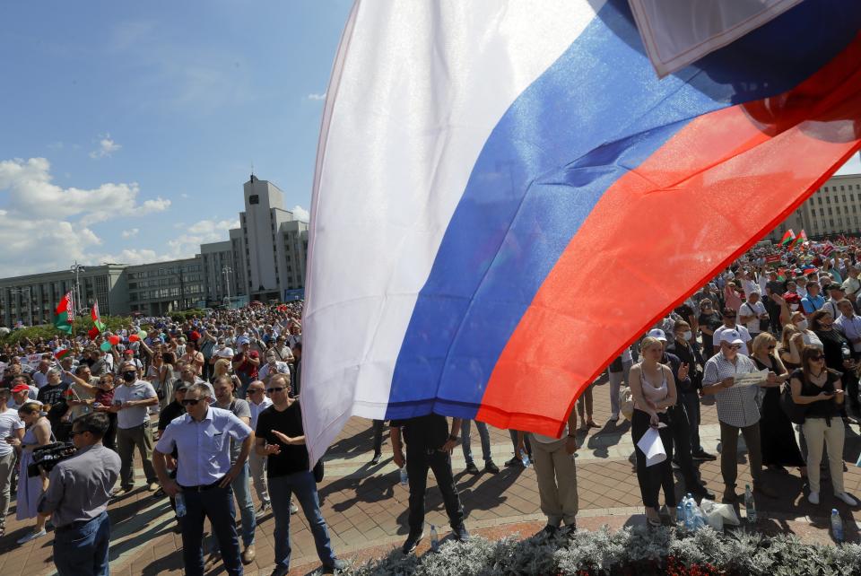 A Russian national flag flies over supporters of Belarusian President Alexander Lukashenko with Belarusian State flags gather at Independent Square of Minsk, Belarus, Sunday, Aug. 16, 2020. Thousands of people have gathered in a square near Belarus' main government building for a rally to support President Alexander Lukashenko, while opposition supporters whose protests have convulsed the country for a week aim to hold a major march in the capital. (AP Photo/Sergei Grits)