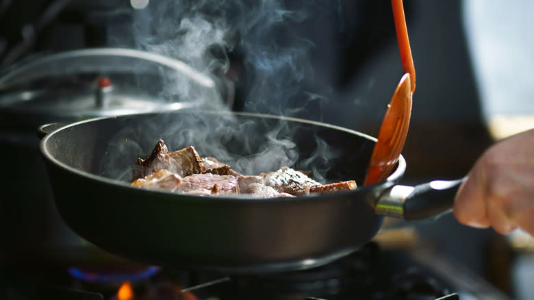 Man cooks meat in a pan 