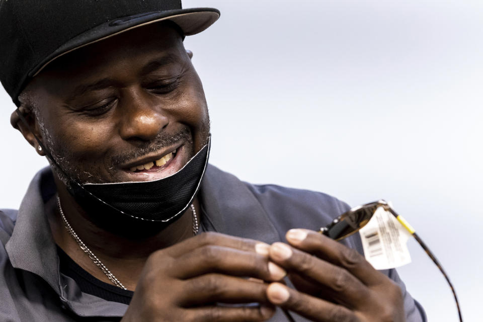 Harold Lewis, a recovering drug user, looks at a pair of sunglasses he won by picking paper slips with prizes written on them out of a fishbowl, Monday, July 18, 2022 at Liberation Programs in Bridgeport, Conn. “Recovery is just not all balled-up fists and clutched teeth, you know what I mean?" Lewis says. “It can be fun, where you can exhale and you can breathe and get excited — because you don’t know what you’re going to win today.” (AP Photo/Julia Nikhinson)