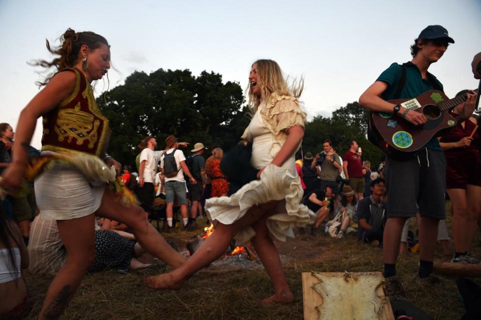 A festivalgoer plays the guitar as others dance around a bonfire (AFP/Getty)