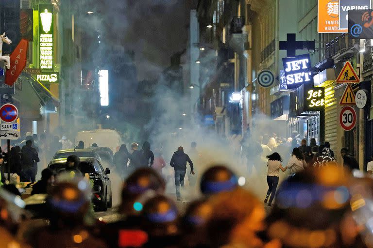 Los manifestantes corren mientras los policías franceses usan gases lacrimógenos en París el 2 de julio de 2023, cinco días después de que la policía matara a un joven de 17 años en Nanterre, un suburbio al oeste de París