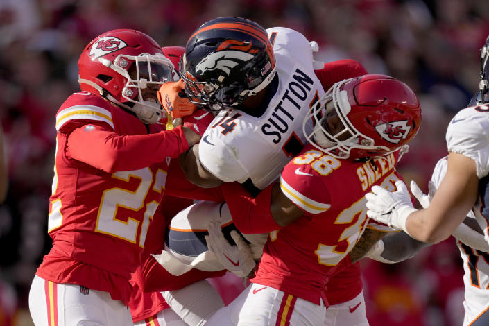 Denver Broncos wide receiver Courtland Sutton (14) is stopped by Kansas City Chiefs safety Juan Thornhill (22) and cornerback L'Jarius Sneed (38) after catching a pass during the first half of an NFL football game Sunday, Jan. 1, 2023, in Kansas City, Mo. (AP Photo/Charlie Riedel)