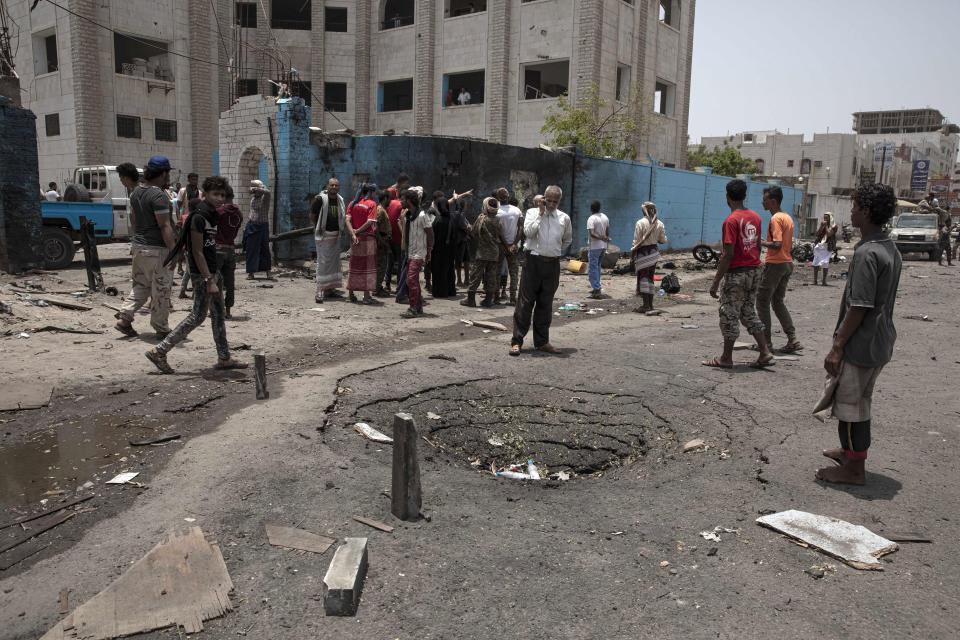 Civilians and security forces gather at the site of a deadly attack, in Aden, Yemen, Thursday, Aug. 1, 2019. Yemen's rebels fired a ballistic missile at a military parade Thursday in the southern port city of Aden as coordinated suicide bombings targeted a police station in another part of the city. The attacks killed over 50 people and wounded dozens. (AP Photo/Nariman El-Mofty)