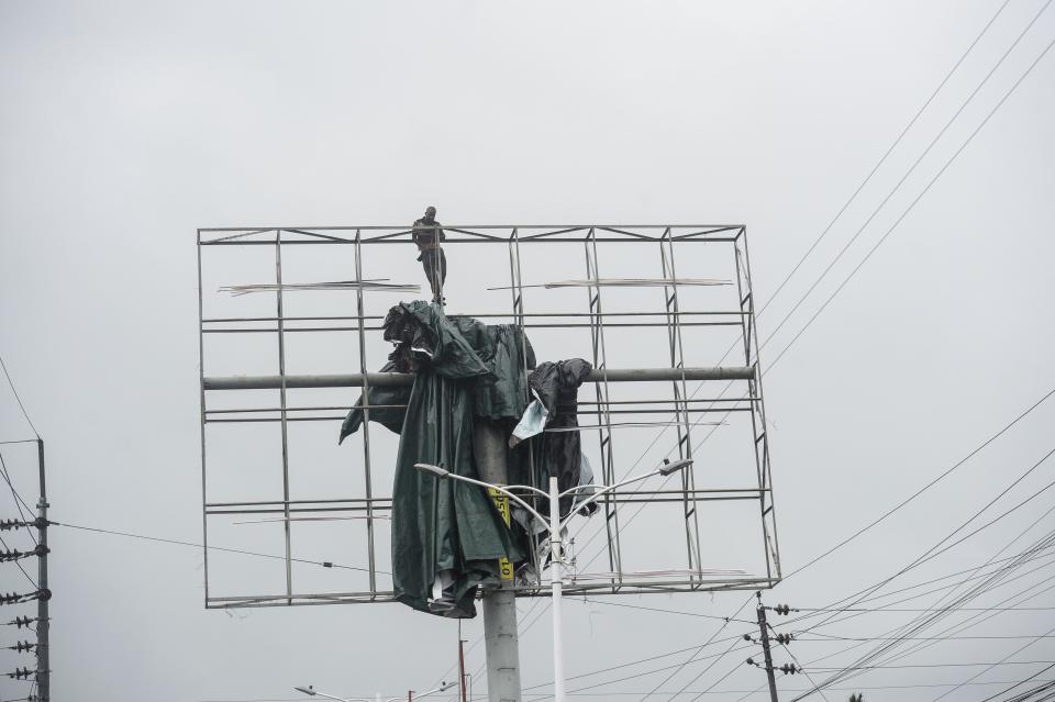 A worker removes a tarpaulin from an advertising structure ahead of the expected landfall of cyclone Amphan, in Khulna on May 20, 2020. (Photo by MUNIR UZ ZAMAN/AFP via Getty Images)