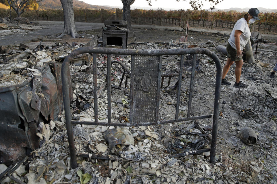 Bernadette Laos looks for salvageable items in her home that was destroyed by the Kincade Fire near Geyserville, Calif., Thursday, Oct. 31, 2019. (AP Photo/Charlie Riedel)