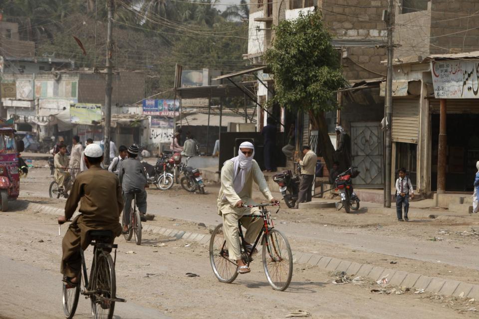 In this Wednesday, Feb. 26, 2014 photo, Pakistani men ride their bicycles in a street of Quaidabad area of Karachi, Pakistan. 44 police officers were killed in the line of duty during the first two months of the year in Karachi, marking a particularly violent beginning of the year for police. This spike came after the police were already reeling from the killings of 166 officers last year _ roughly one every other day and a four-fold increase from just five years earlier. (AP Photo/Shakil Adil)