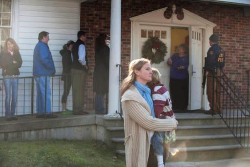 Una mujer carga a un niño en una iglesia cercana la escuela donde ocurrió la matanza en Connecticut.