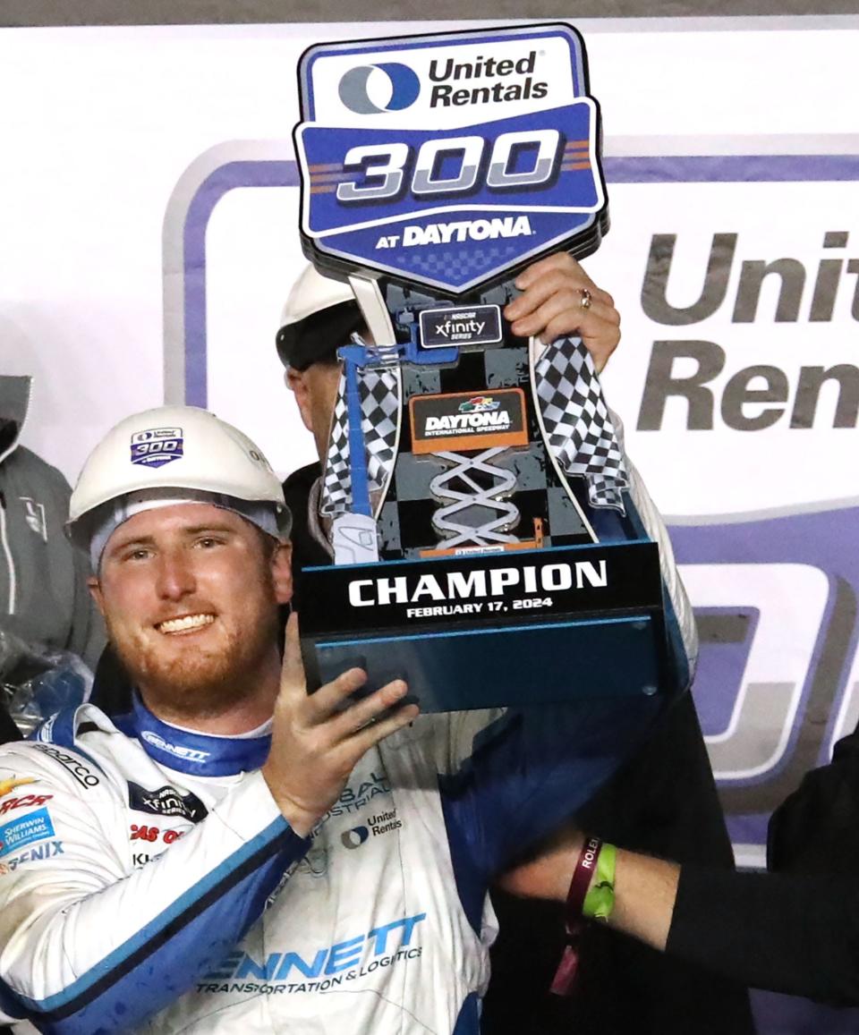 Austin Hill lifts the winners trophy in Victory Lane, Friday, February 19, 2024 after winning the United Rentals 300 at Daytona International Speedway.