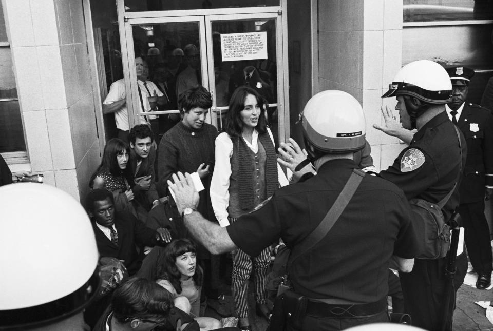 Singer Joan Baez (C) is stopped by police, as they advise her of her Constitutional rights, just prior to her arrest in front of the Oakland Induction Center on Oct. 16, 1967. Miss Baez and some 75 others were arrested as they attempted to block draftees from entering the center. More than 600 persons took place in the demonstration. (Bettmann Archive via Getty Images)