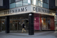 A man wearing a face mask walks past the Debenhams flagship department store on Oxford Street, during England's second coronavirus lockdown in London, Tuesday, Dec. 1, 2020. In another dark day for the British retailing industry, Debenhams said Tuesday it will start liquidating its business after a potential buyer of the company pulled out, a move that looks like it will cost 12,000 workers their jobs. (AP Photo/Matt Dunham)