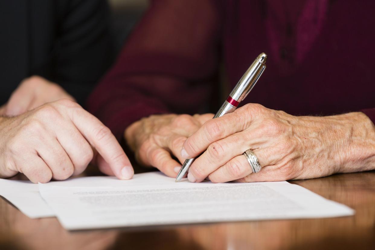 hand indicating where to sign contact, elderly hand with pen signing