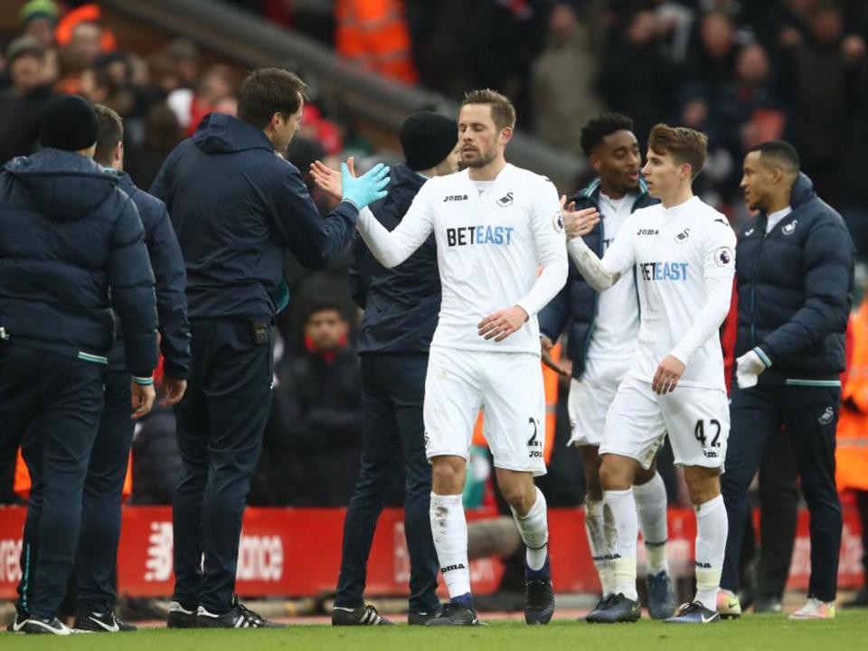 Gylfi Sigurdsson is congratulated after securing Swansea victory at Liverpool (Getty)