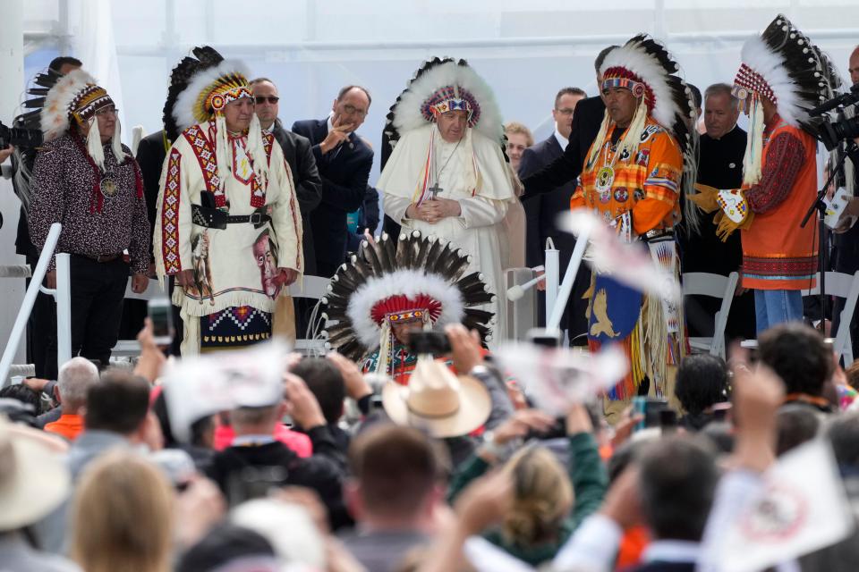 Pope Francis puts on an indigenous headdress during a meeting with indigenous communities, including First Nations, Metis and Inuit, at Our Lady of Seven Sorrows Catholic Church in Maskwacis, near Edmonton, Canada, Monday, July 25, 2022. Pope Francis begins a "penitential" visit to Canada to beg forgiveness from survivors of the country's residential schools, where Catholic missionaries contributed to the "cultural genocide" of generations of Indigenous children by trying to stamp out their languages, cultures and traditions. Francis set to visit the cemetery at the former residential school in Maskwacis. 