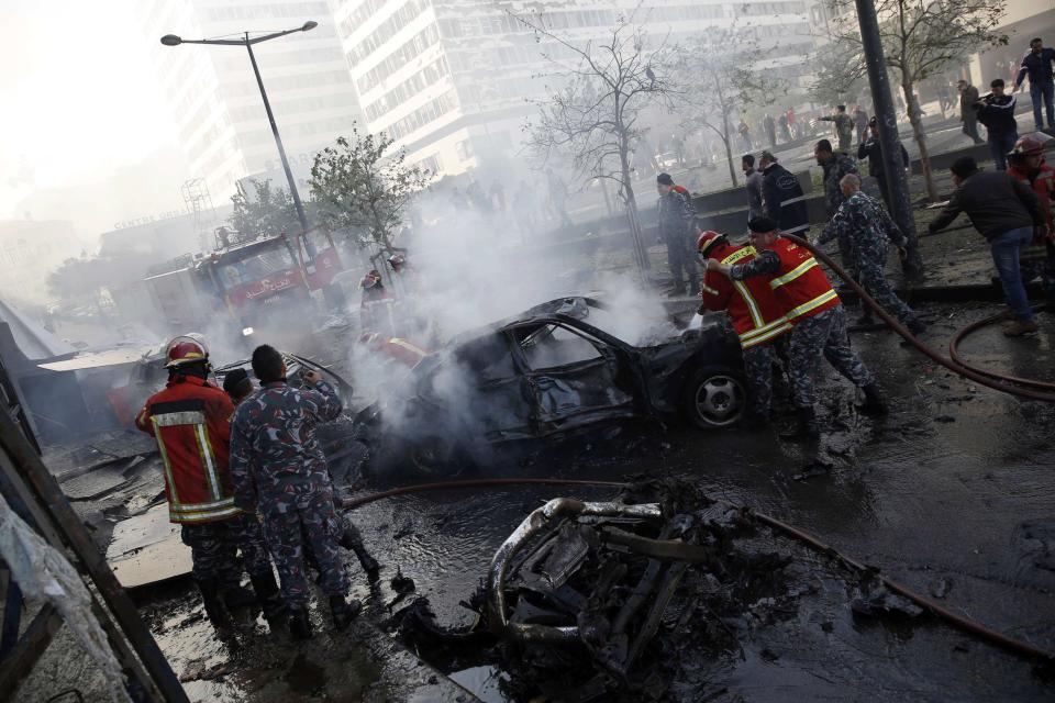 Civil Defence personnel extinguish fires on cars at the site of an explosion in Beirut downtown area