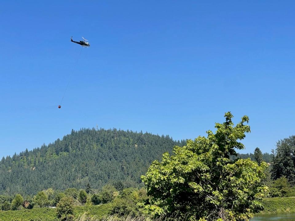 A helicopter approaches water to refill a bucket while working to douse the Sodaville Cutoff Fire outside Lebanon on Tuesday, Aug. 1, 2023.