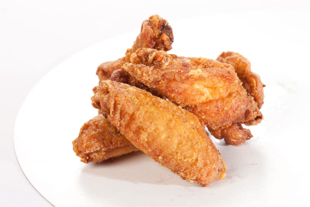 Look, Manchu wings do not look like this. If they did, theGrio would not be sending you there. This photo is for informational purposes only – to show you a picture of chicken. Manchu comes in a cardboard box, not on a pristine white plate. (Adobe Stock Image)