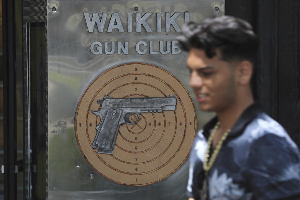 People walk past the Waikiki Gun Club, Thursday, June, 23, 2022 in Honolulu. In a major expansion of gun rights after a series of mass shootings, the Supreme Court said Thursday that Americans have a right to carry firearms in public for self-defense.