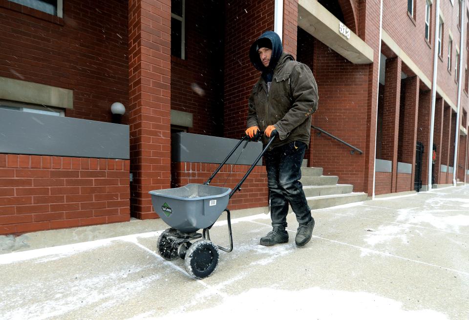 Cleveland Wilson of Springfield puts salt down in front of businesses on Monroe Street as temperatures drop in Springfield Thursday Dec. 22, 2022.