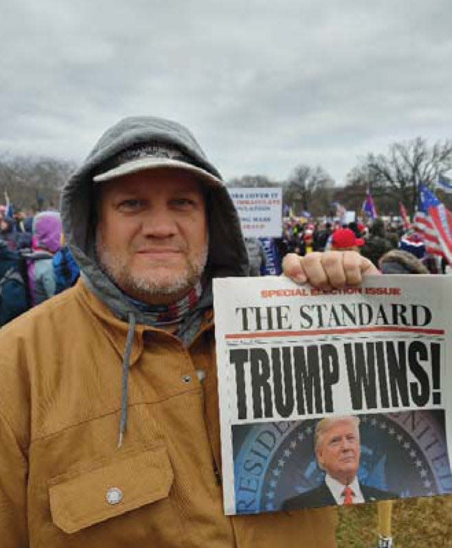 This photo of Jonathan Daniel Carlton holding a souvenir newspaper front was included in an FBI report called a statement of facts that was filed in federal court in Washington. The report said the image came from Bradley Weeks' cell phone.