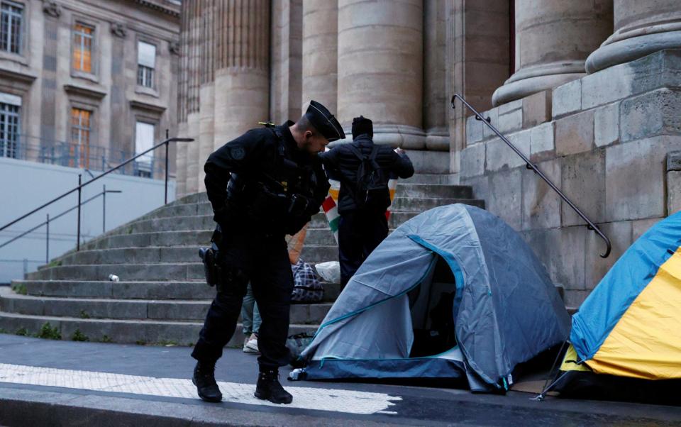 Police look at one of the tents as they evict around 100 migrants from the makeshift camp in central Paris
