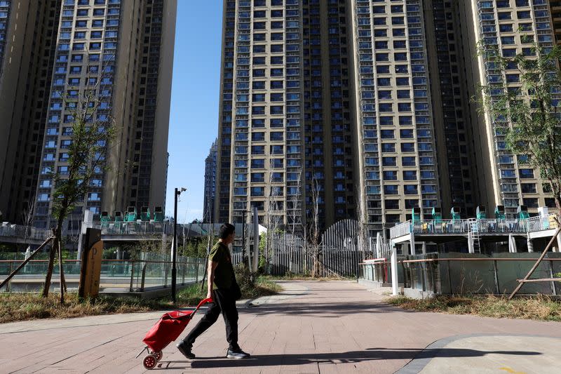 FILE PHOTO: A man pulls a cart past residential buildings at an Evergrande residential complex in Beijing