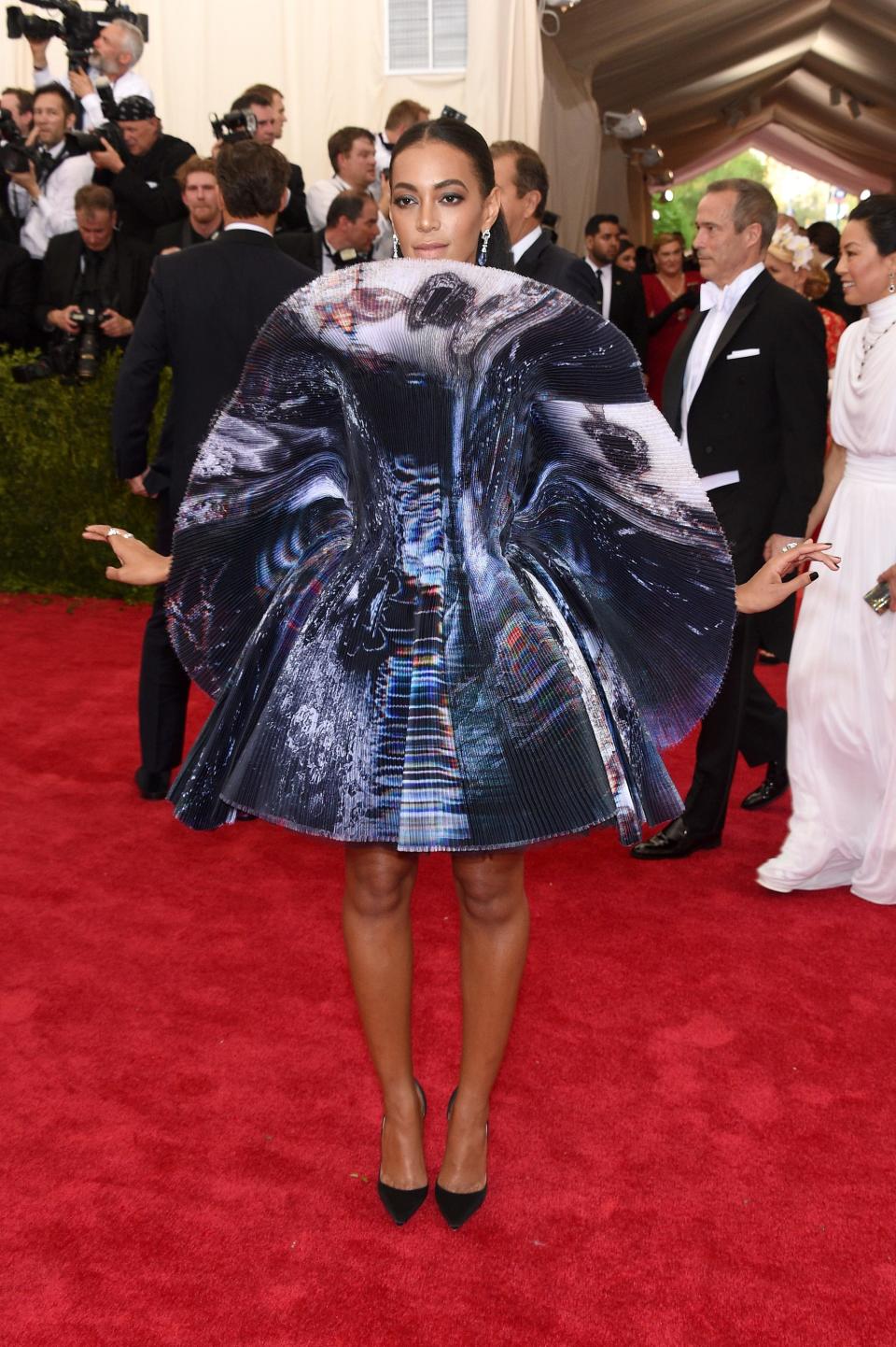 Solange Knowles arrives at the Met Gala wearing a short blue dress with a large, rounded ruffle neck.