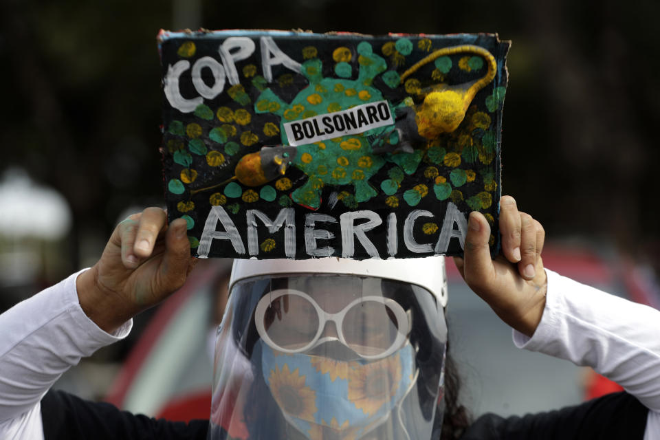 A woman holds a sign to protest against Brazil holding the Copa America in Brasilia, Brazil, Sunday, June 6, 2021. Brazil accepted hosting the South American soccer tournament after the original co-hosts were dropped, Colombia due to political protests and Argentina for rising of COVID-19 cases. (AP Photo/Eraldo Peres)