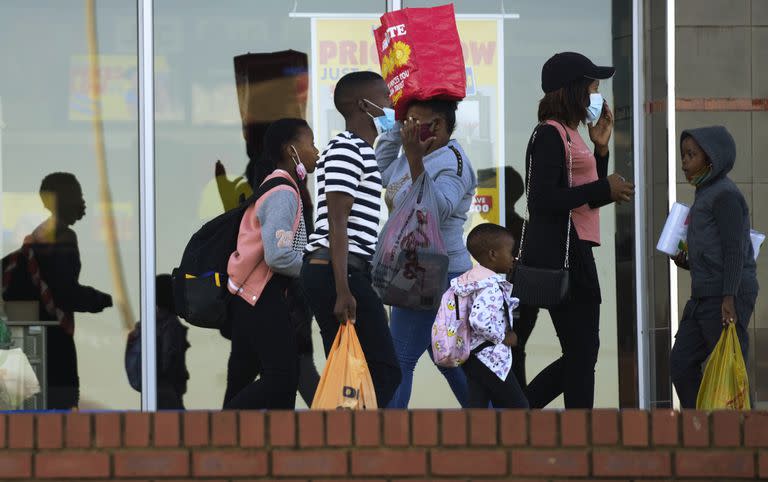 Customers, some wearing mask walks out of grocery store at a shopping mall in Vosloorus, east of Johannesburg, South Africa, Saturday, April 30, 2022. South Africa is seeing a rapid rise in COVID-19 cases driven by yet another version of the coronavirus, health experts say. (AP Photo/Themba Hadebe)