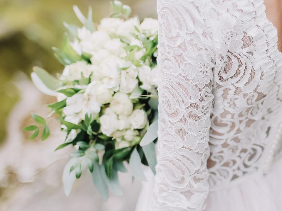 Bride in lace wedding gown with white bouquet of flowers