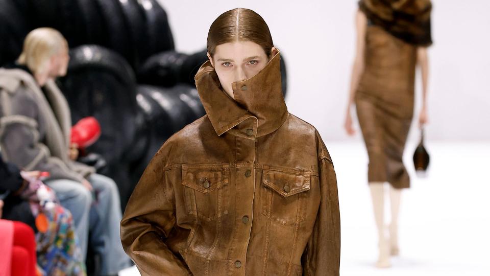 A model walks the runway during the Acne Studios Womenswear Fall/Winter 2024-2025 show wearing a leather jacket and matching leather pants.