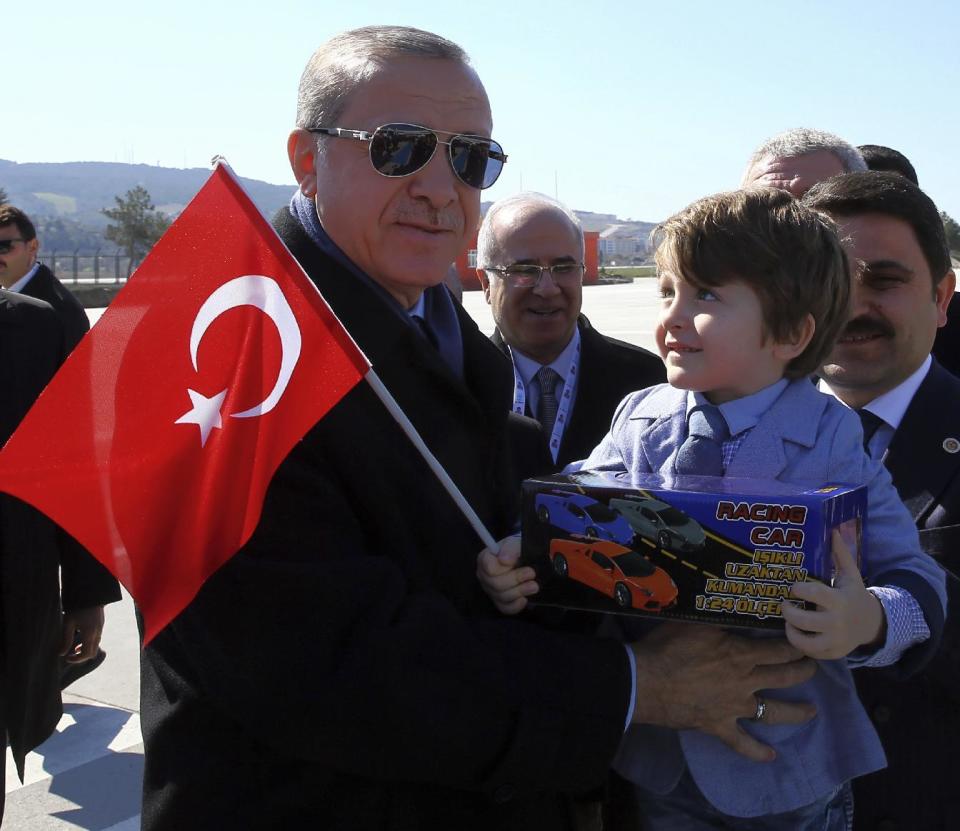 Turkey's President Recep Tayyip Erdogan holds a boy as he arrives to attend a ceremony marking the 102nd anniversary of Gallipoli campaign, in the Aegean port of Canakkale, near Gallipoli where troops under British command landed in 1915, Saturday, March 18, 2017. Cheered by flag-waving supporters, the Turkish president turned a commemoration of a World War I campaign into a political rally on Saturday, slamming Europe and declaring that a constitutional referendum next month on whether to expand his powers will enhance Turkey's place in the world.(Kayhan Ozer/Presidential Press Service, Pool Photo via AP)