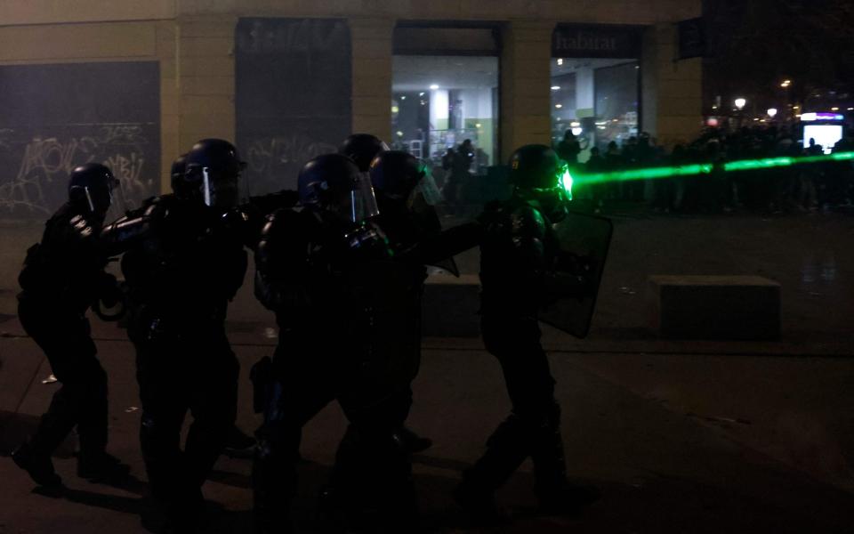 A laser beam points a CRS riot police officer as he faces protesters at Place de la Republique in Paris - AFP