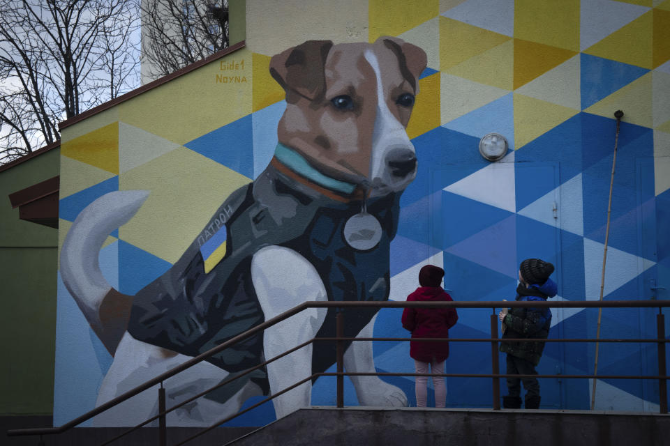 Dos niños observan un mural con la imagen de un terrier llamado Patron, un perro de rastreo que es la mascota del Servicio de Emergencias de Ucrania, en Kiev, Ucrania, el 2 de febrero de 2024. Patron, nacido en 2019, fue premiado dentro y fuera del país por su trabajo localizando y desactivando explosivos que dejaron atrás las tropas rusas. En noviembre de 2022, UNICEF lo reconoció como "Embajadog de buena voluntad" -- un juego de palabras con la palabra perro (dog en inglés) y embajador -- en Ucrania. (AP Foto/Efrem Lukatsky)