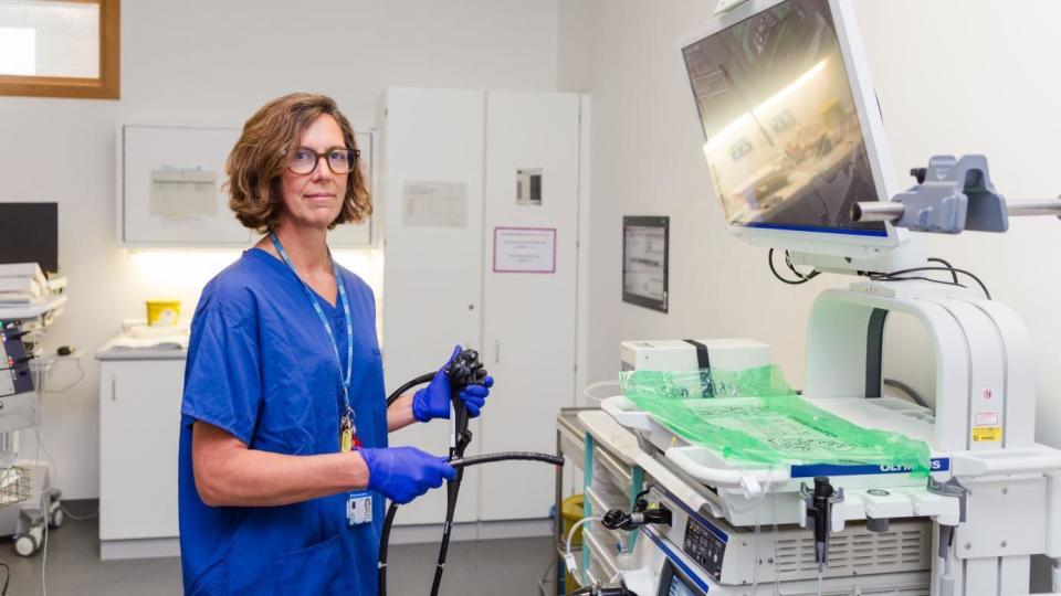 A doctor wearing blue scrubs standing in an endoscopy theatre
