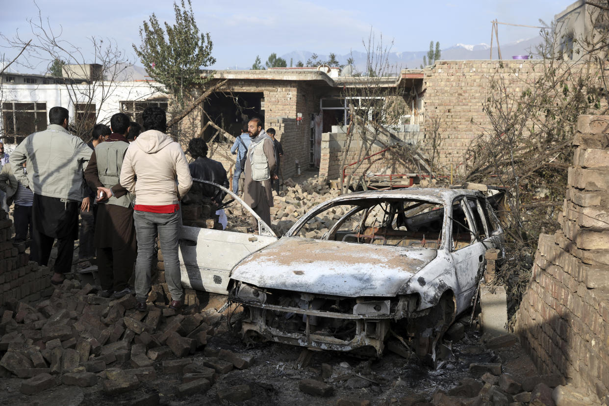 Residents view vehicles and a house damaged in a fire that consumed oil tankers and trucks in Kabul, Afghanistan, Sunday, May 2, 2021. A fire roared through several fuel tankers on the northern edge of the Afghan capital late Saturday, injuring at least 10 people and plunging much of the city into darkness, officials said. (AP Photo/Rahmat Gul)