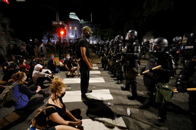A protester stands to face riot policemen during nationwide unrest following the death in Minneapolis police custody of George Floyd, in Raleigh