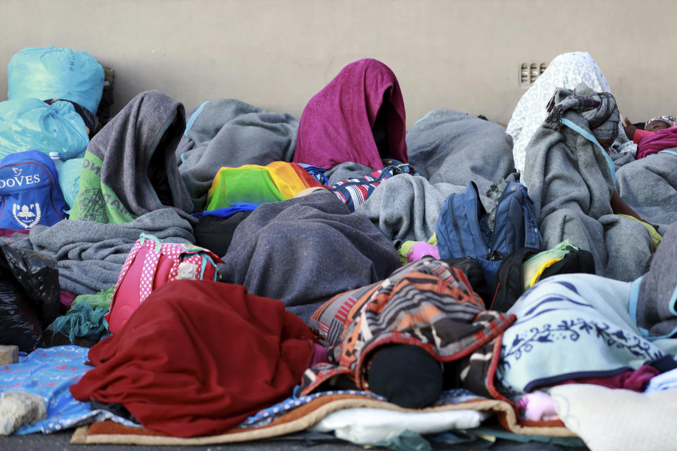 Refugees sleep on a sidewalk in Cape Town, South Africa, Friday, March 27, 2020, after South Africa went into a nationwide lockdown for 21 days in an effort to mitigate the spread to the coronavirus. The new coronavirus causes mild or moderate symptoms for most people, but for some, especially older adults and people with existing health problems, it can cause more severe illness or death. (AP Photo/Nardus Engelbrecht)