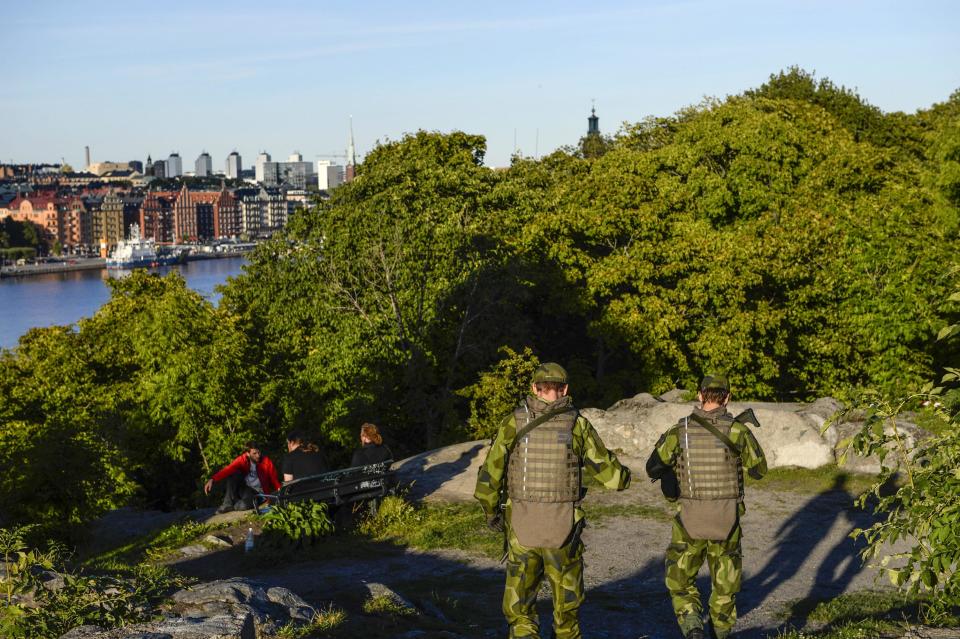 Soldiers patrol the Langholmen island, while some people relax on a park bench, in central Stockholm, Tuesday Sept. 3, 2013. Security was beefed up and parts of city were cordoned off on the eve of the two-day visit to Sweden by U.S. President Barack Obama. (AP Photo / TT News Agency / Henrik Montgomery) SWEDEN OUT