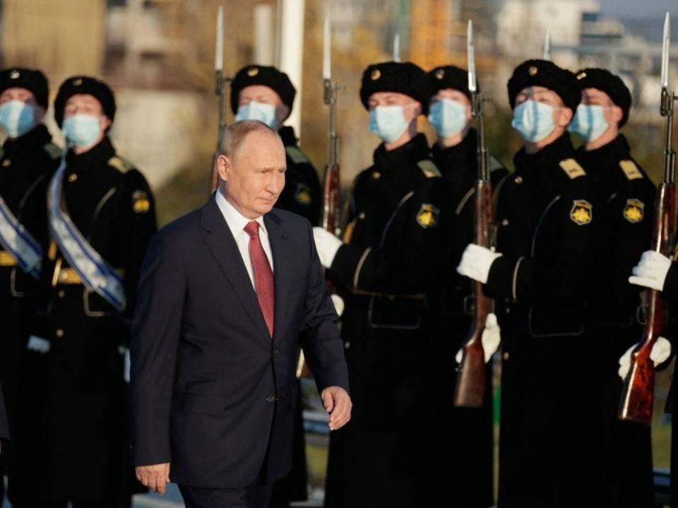 Russian President Vladimir Putin walks past military personnel during a ceremonial event.